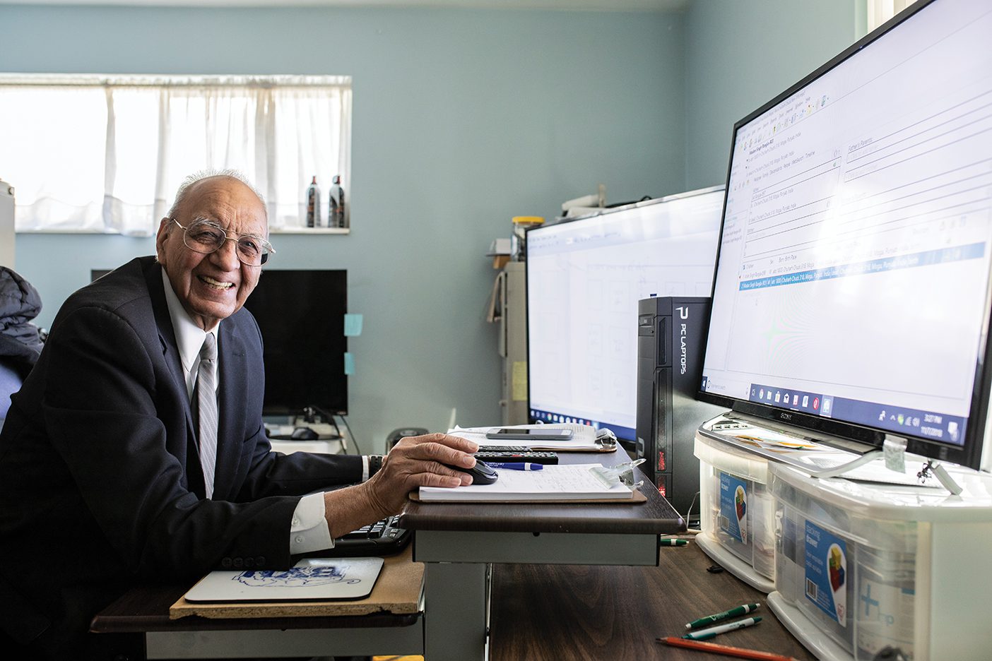 Gurcharan Gill smiles from his desk, working on a family history project on the computer.