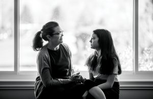 A mother and daughter hold hands and talk.