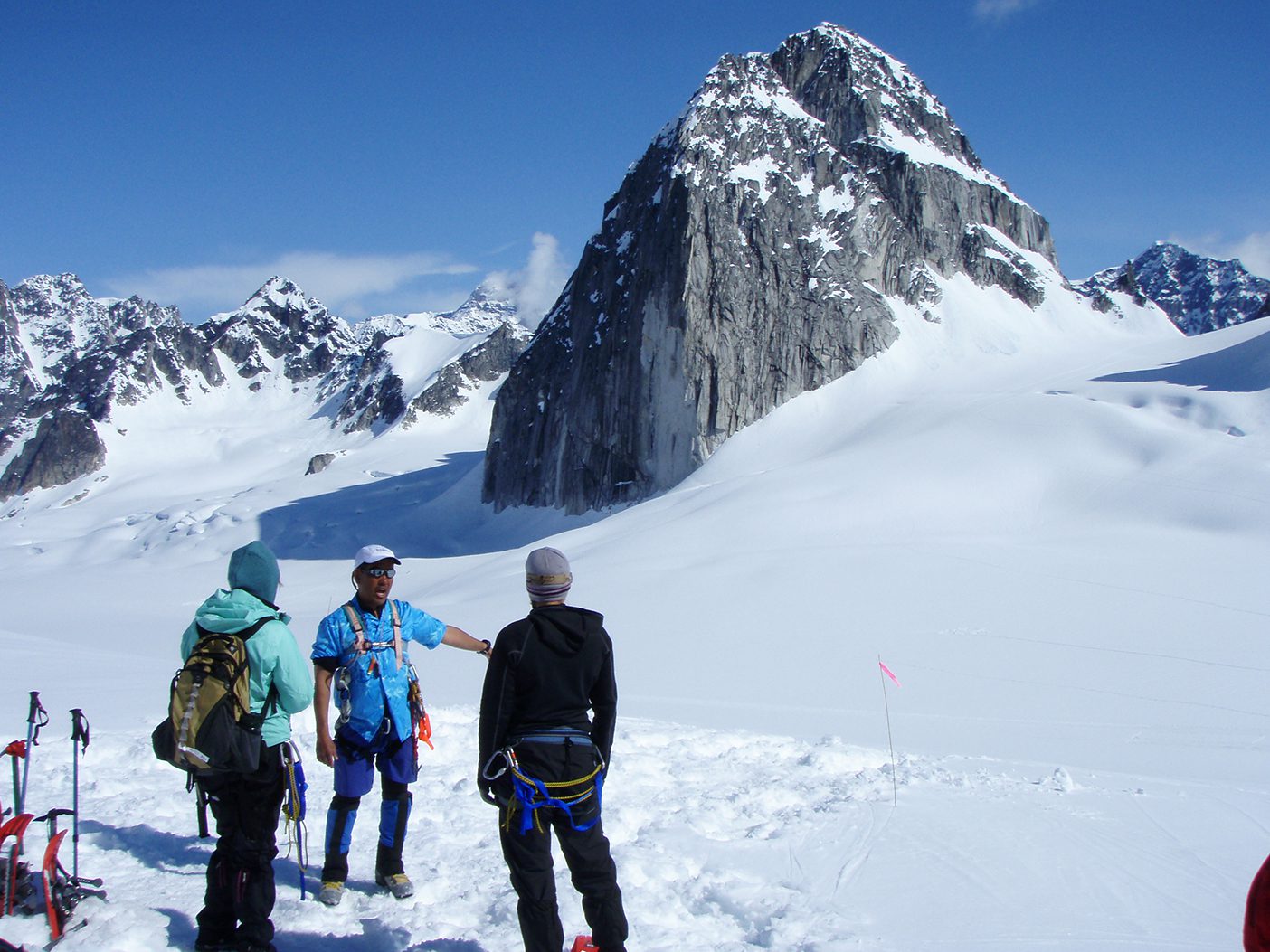 Stacy Taniguchi, donning an aloha shirt, talks to BYU students in the middle of a snowy field in Alaska's "Little Switzerland." The Throne, a huge granite monolith, can be seen in the background.