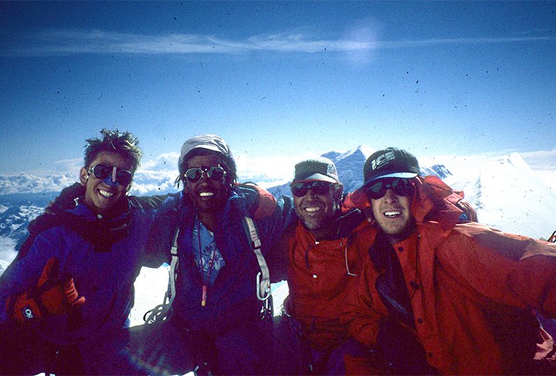 Jared Taniguchi and his dad, Stacy Taniguchi, pose arm in arm with their comrades on the top of Denali, the tallest peak in North America.