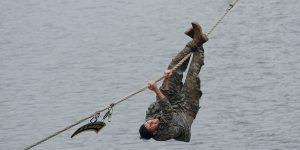 Anna Hodge dangles upsidedown from a rope over a body of water.