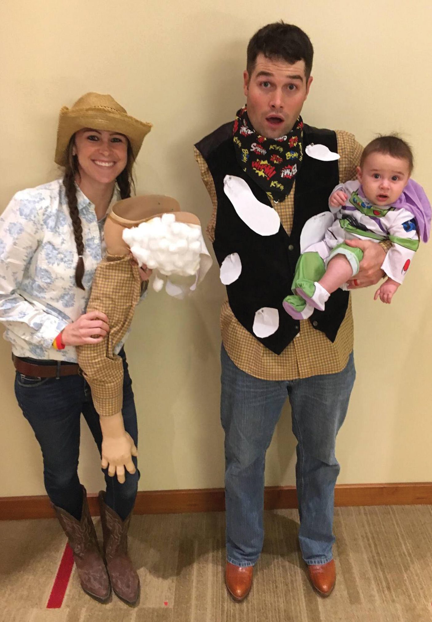 The family in Toy Story costumes: Carlie dressed as Jessie, holding Woody's unattached arm, Porter as an armless Woody, and their son as Buzz Lightyear,