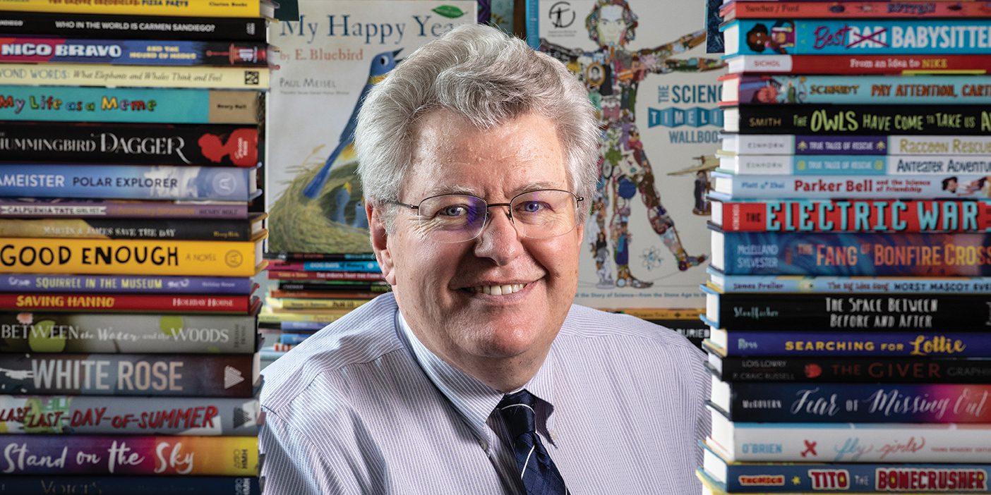 Terrell Young poses between two stacks of books