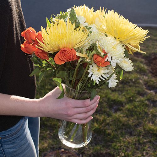 A woman is holding a vase of flowers.