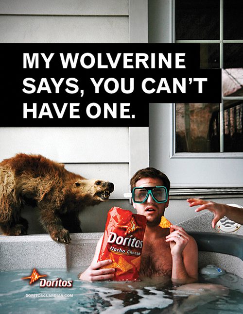 A man sits in a hot top with snorkeling goggles on as he eats from a bag of Doritos. A hand is seen coming from the right side of the ad grabbing for the chips, and a wolverine snarls in defense. Above, text reads, "My wolverine says, you can't have one."