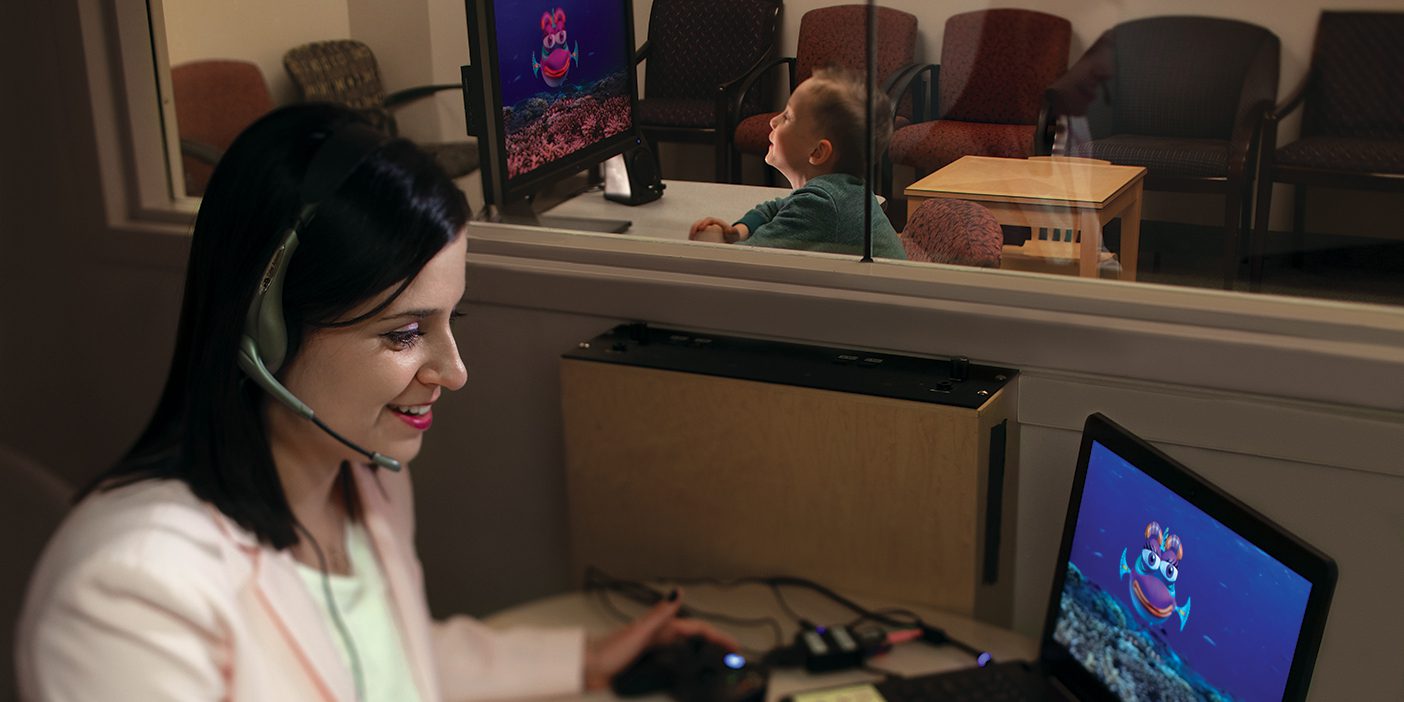 A woman interacts with an autistic boy via a computer animation of a talking fish.