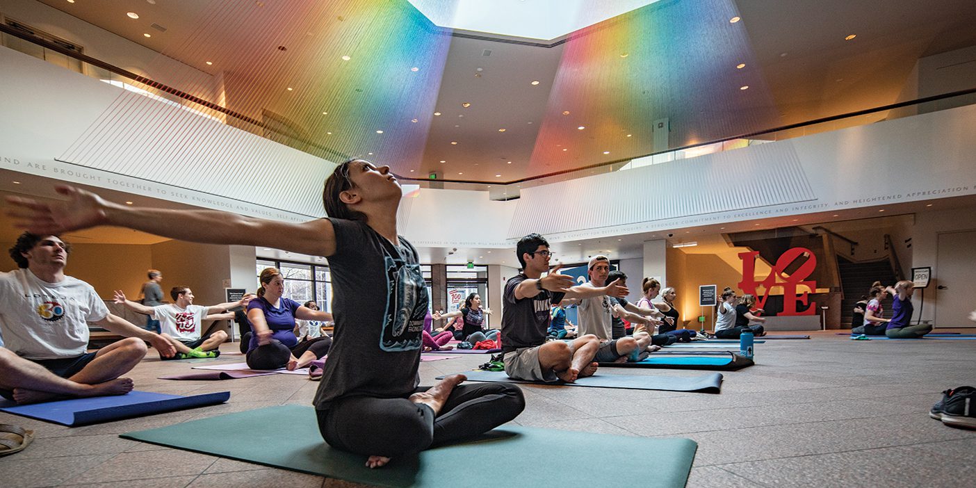 A woman sits on a yoga mat doing a yoga pose in the MOA.