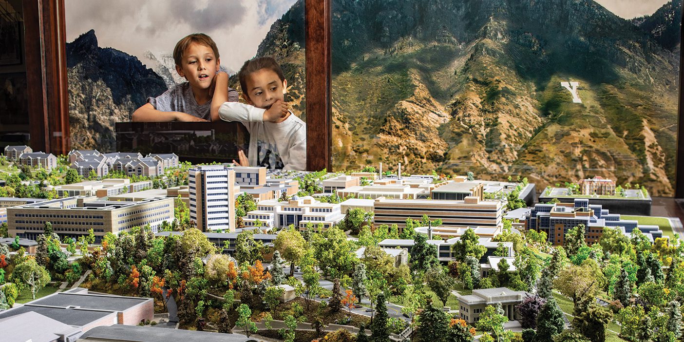 Two young boys admire a large lego model of BYU campus from behind the glass.