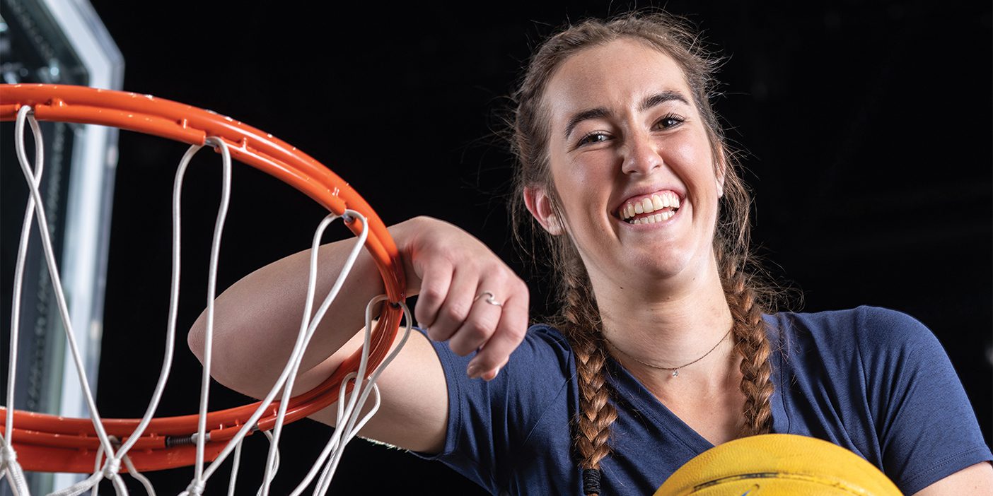 Camdyn Roberts is pictured standing next to the basketball hoop with a big smile on her face.