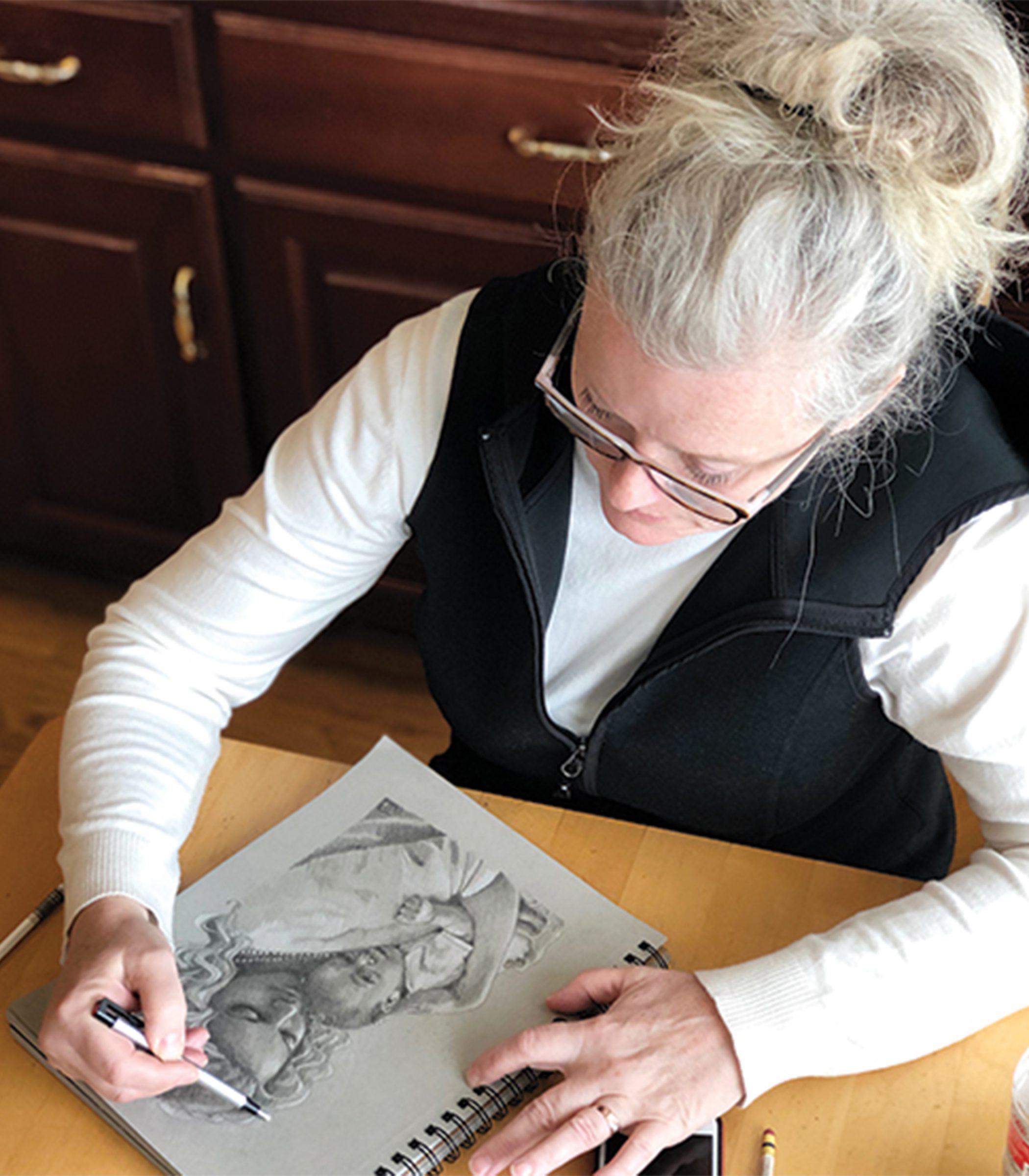 Jean draws a woman holding her child in colored pencil.