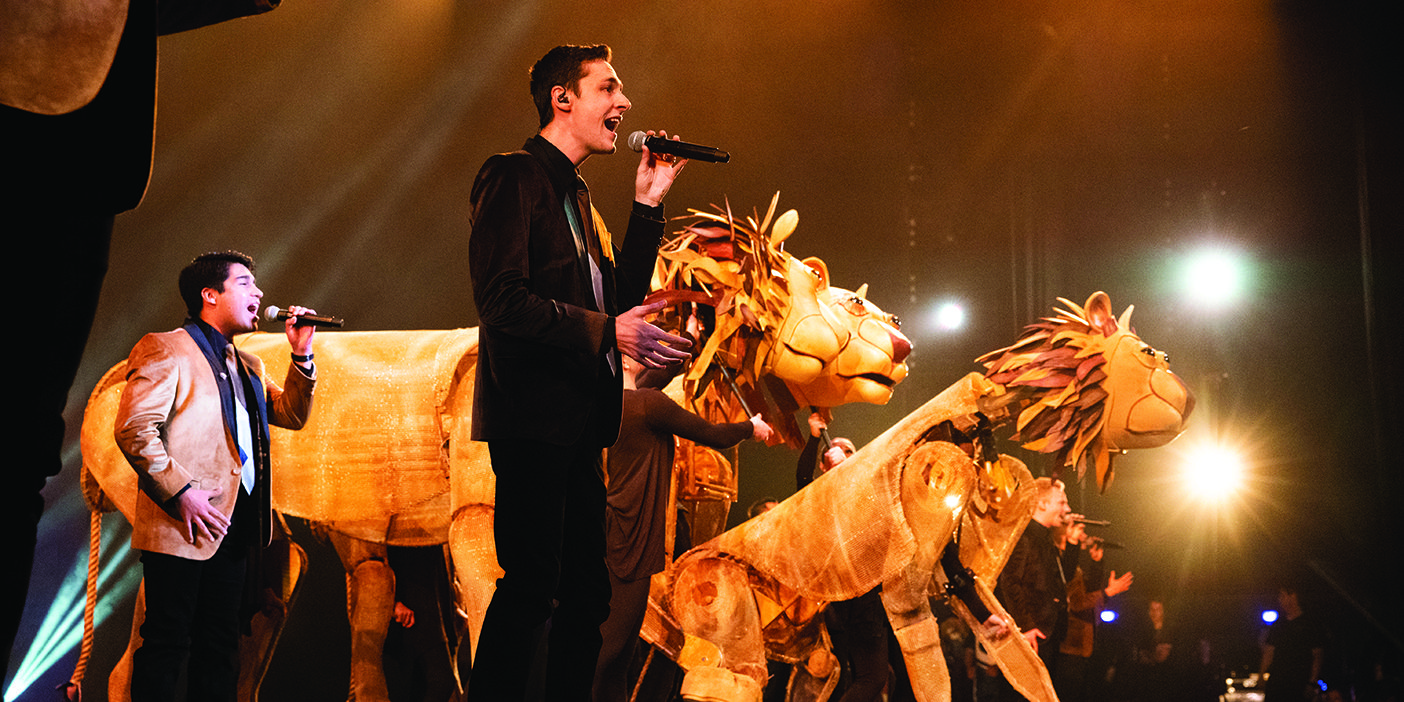 Members of BYU Vocal Point perform alongside larger-than-life lion puppets.