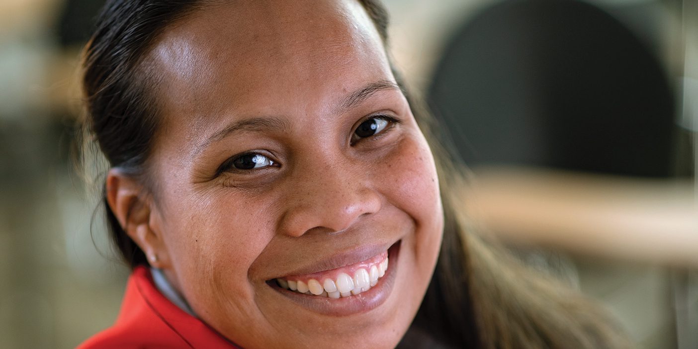 A smiling woman who has a Kiribati flag wrapped around her.