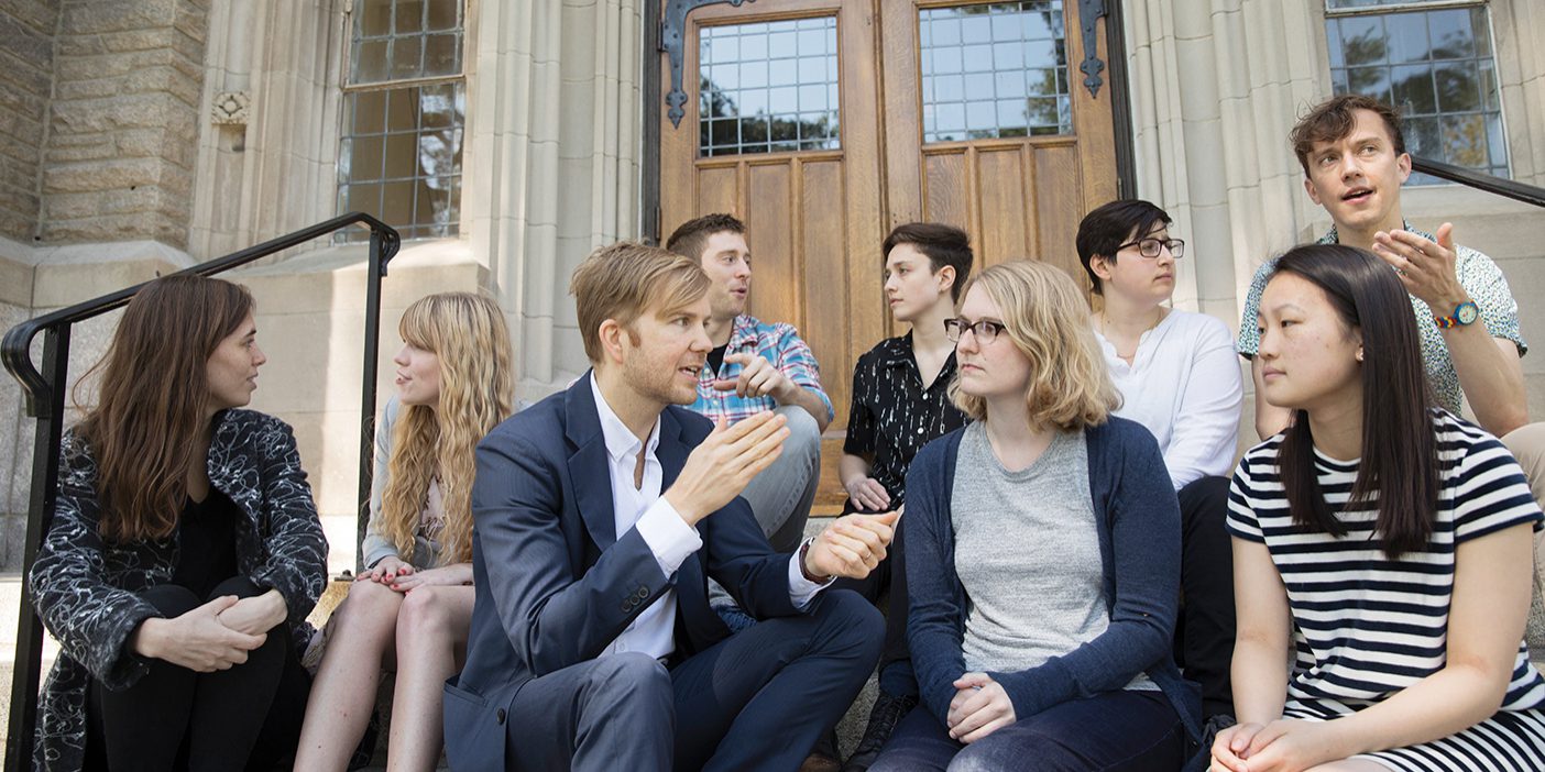 Zachary Davis and his Harvard team, which looks to be made up of students from Harvard, sit on the steps of an older building.