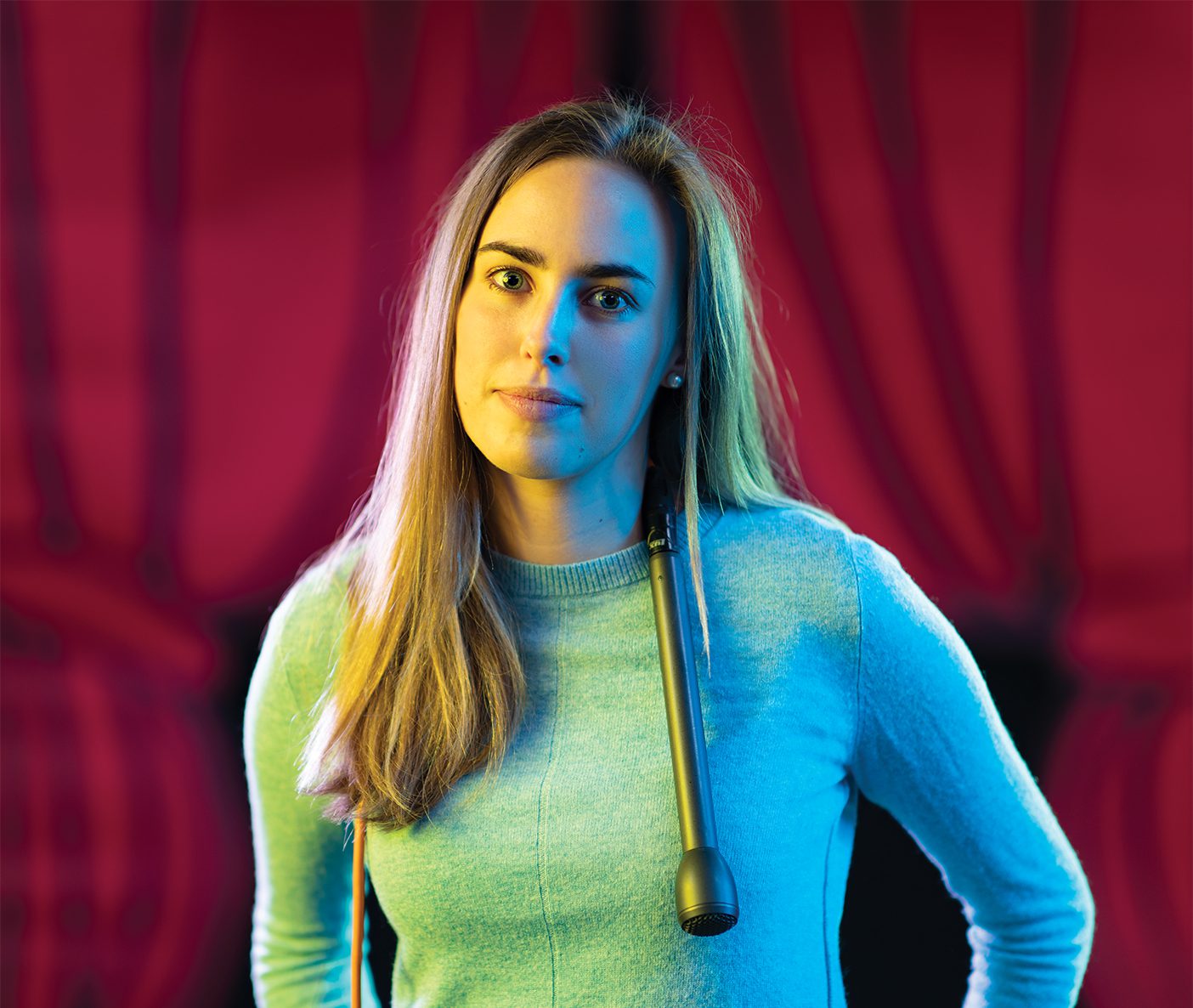 The 2019 BYU George H. Brimhall Memorial Essay Contest winner Hope Thomas stands in front of a red velvet curtain with a microphone draped around her shoulders. She tried stand-up comedy in her "semester-of-putting-myself-out-there."