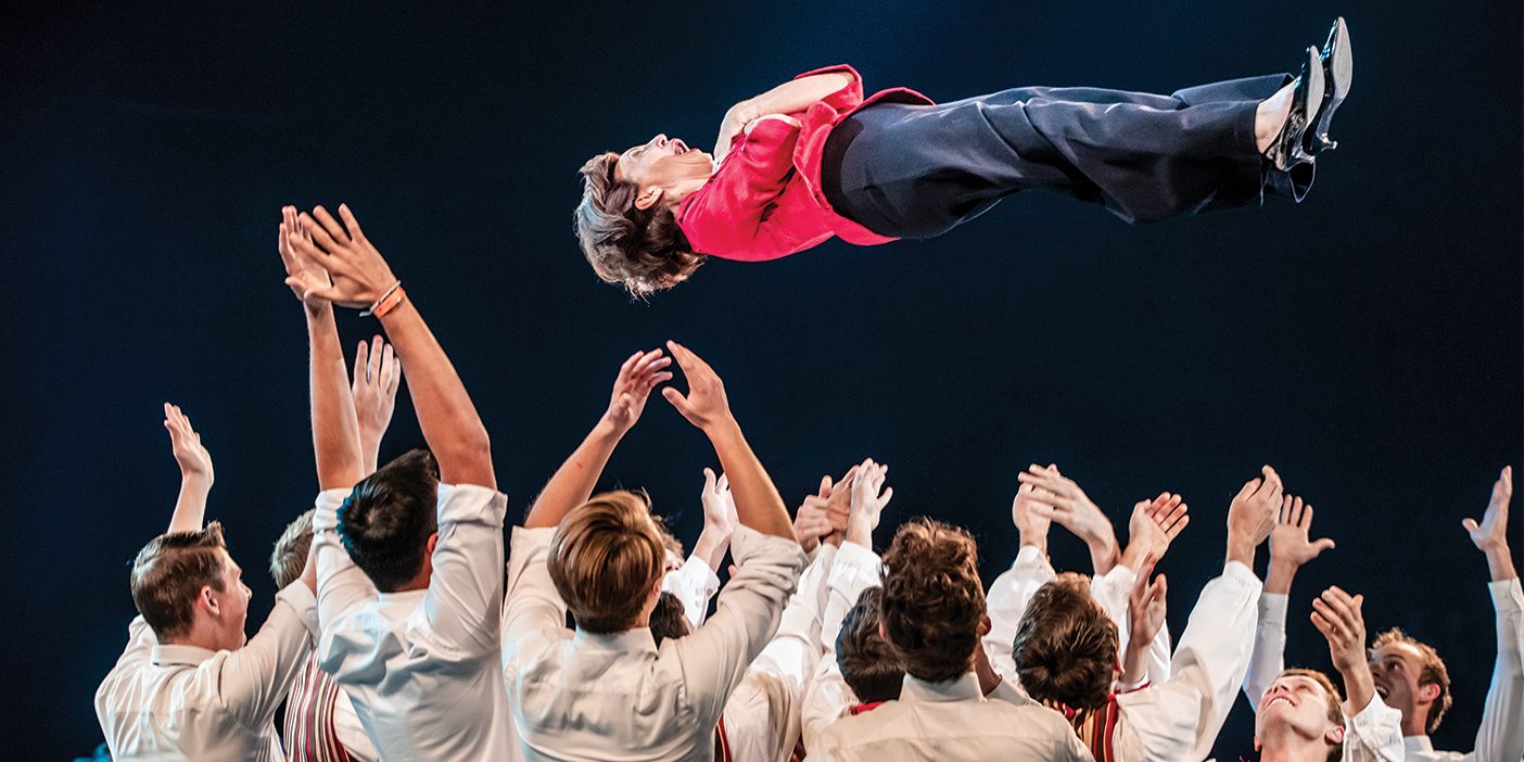 BYU Men's Chorus director Rosalind Hall is thrown in the air by a group of students.