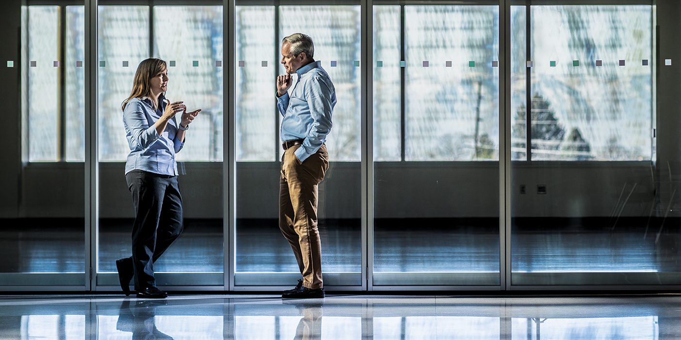 A man and woman have a discussion in a hallway.