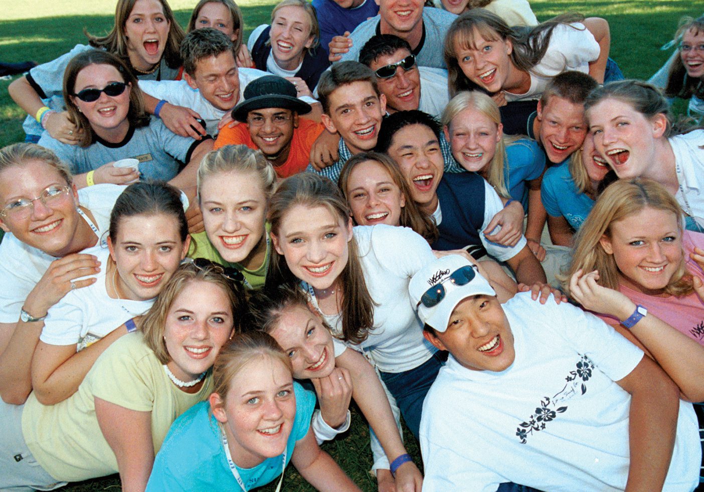 A group of EFY attendees smile as they dog pile out on a grassy field.