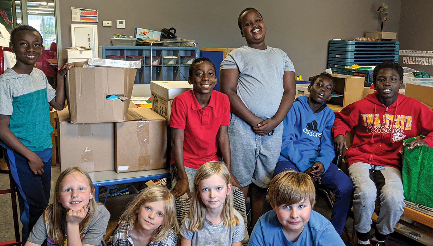 Children smile at a service project where they are boxing books for immigrant children.