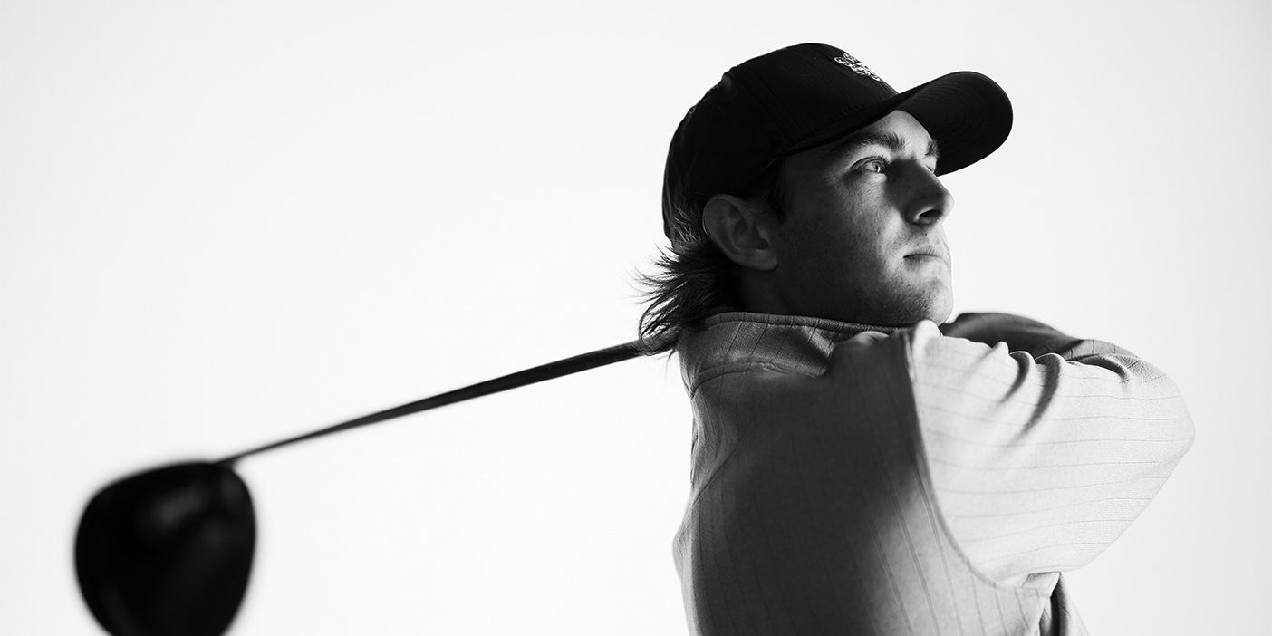 A black and white photo of golfer Peter Kuest as he finishes his swing.