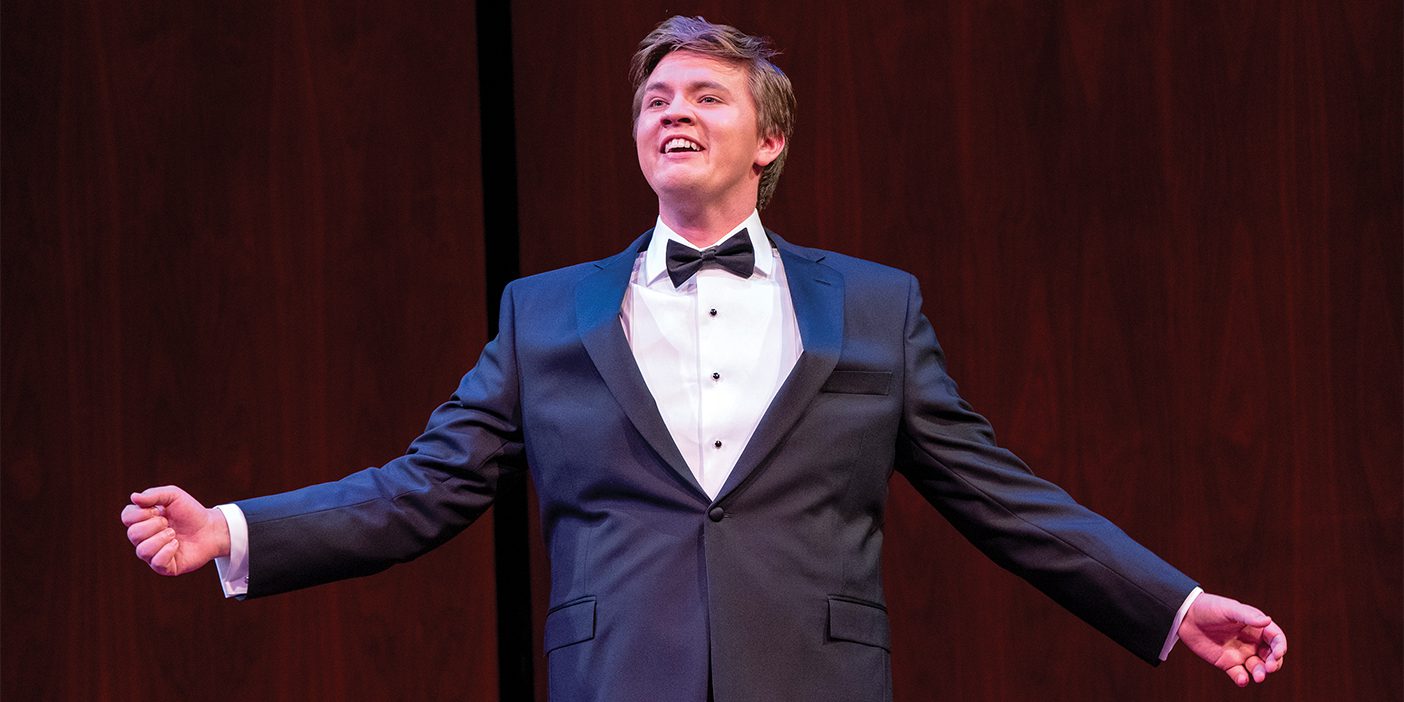 Jonah Hoskins stands on stage with his arms held out as he sings at the Metropolitan Opera National Council Auditions.