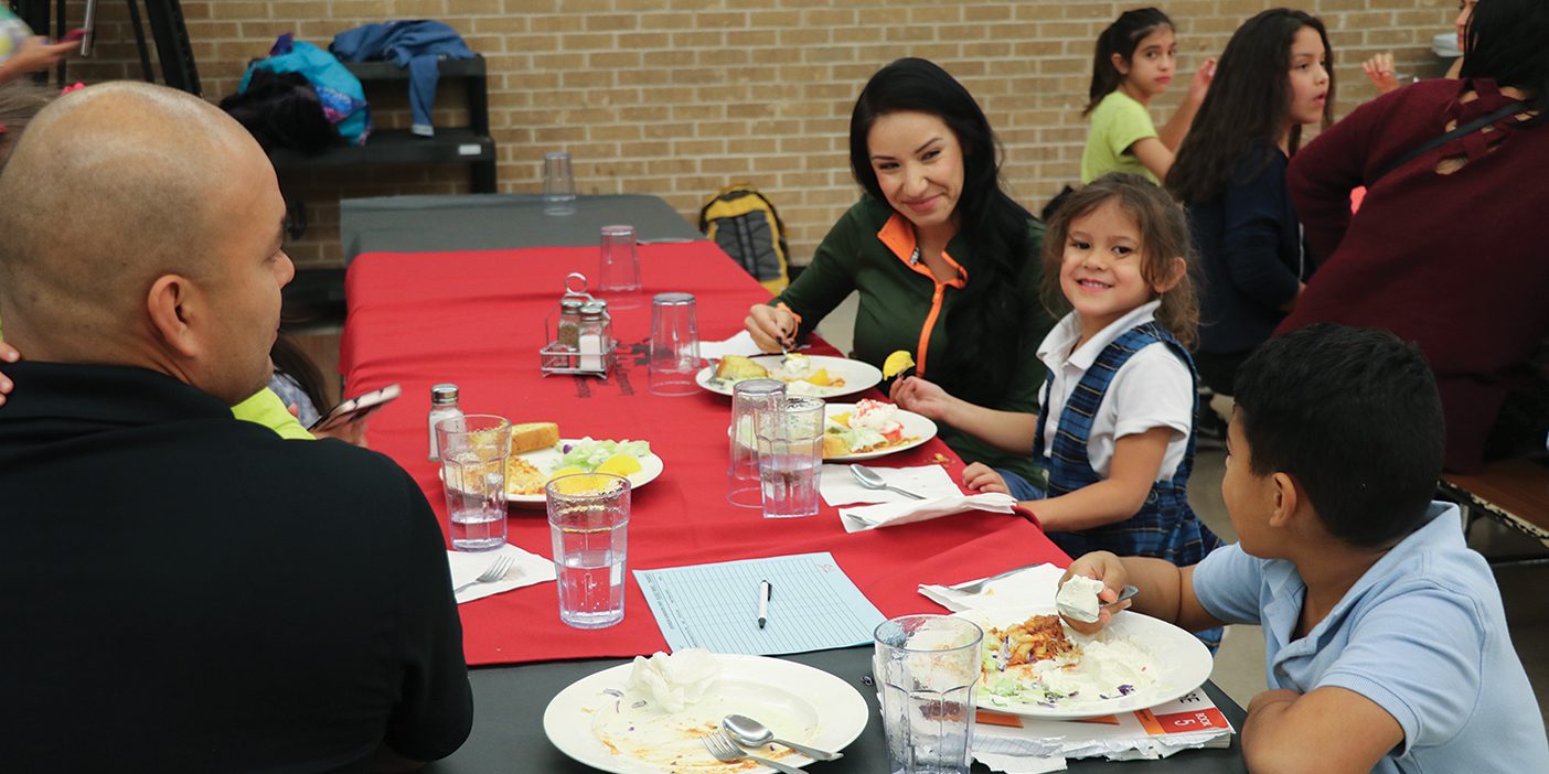 Parents and students sit at a dinner table together in the Homework Diner.