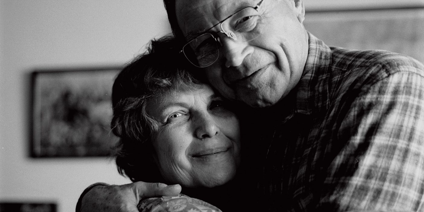 A smiling older couple embrace.