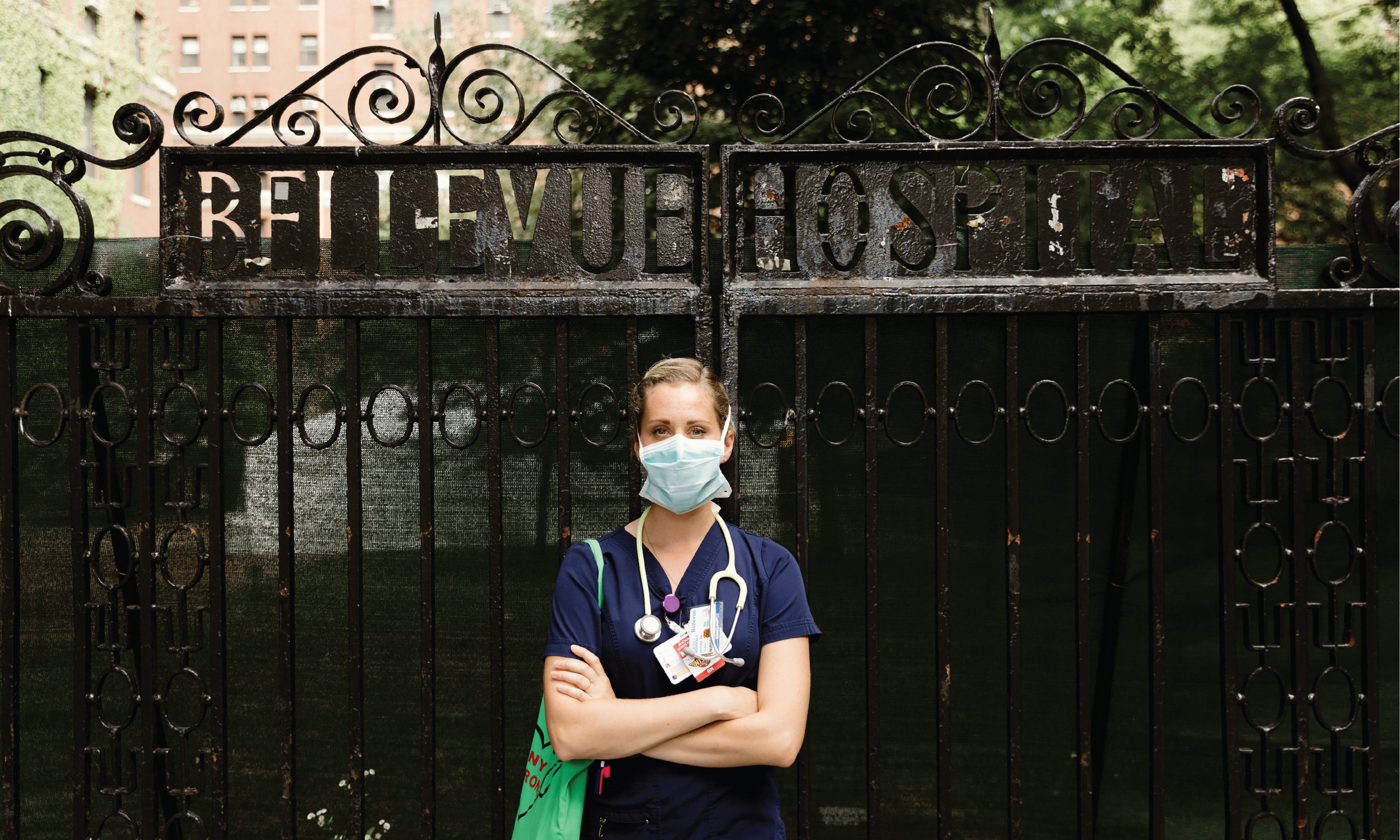 Channing Voyles stands with arms crossed in scrubs and a surgical mask outside the gates of Bellevue Hospital.