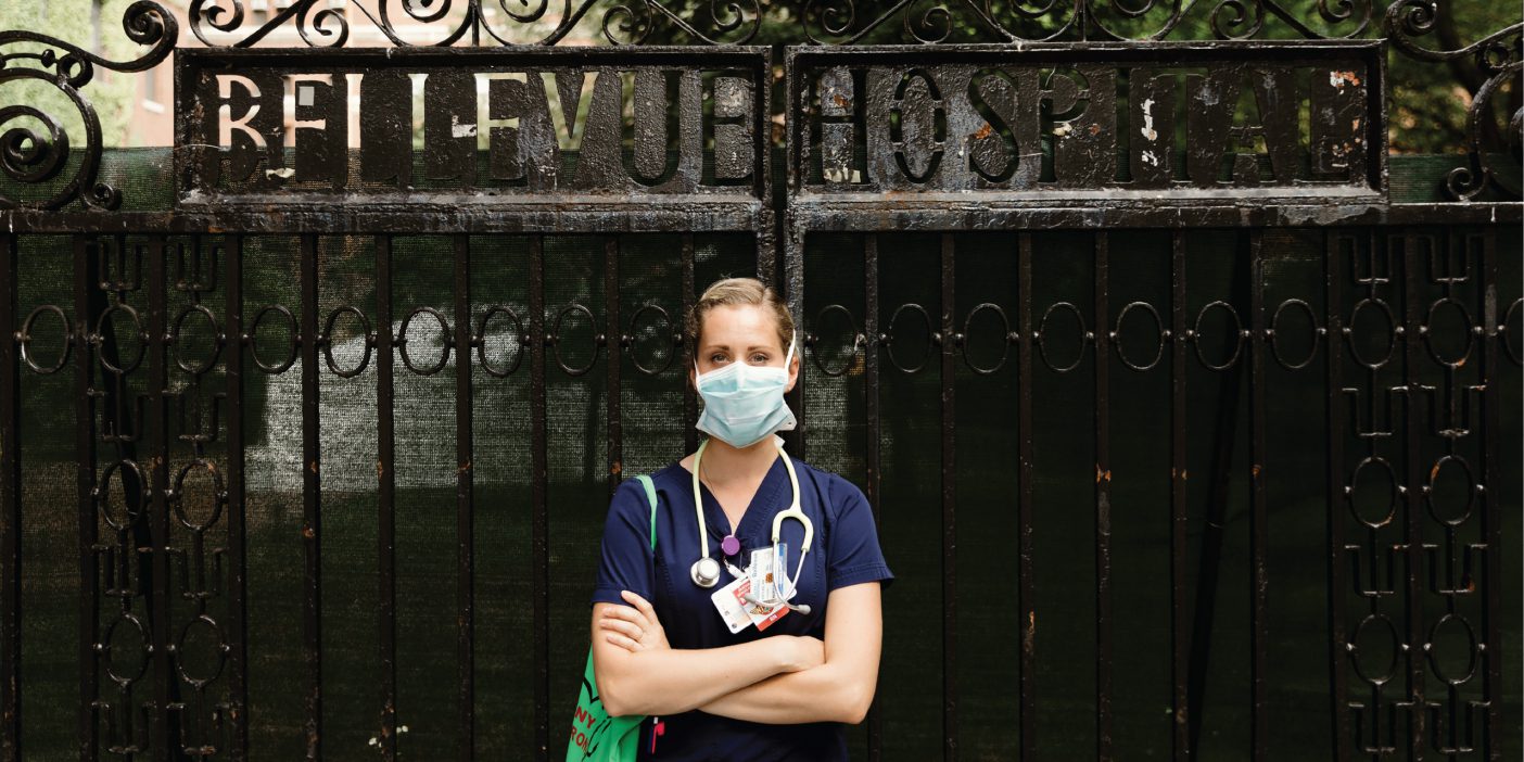 Channing Voyles stands with arms crossed in scrubs and a surgical mask outside the gates of Bellevue Hospital in New York City.