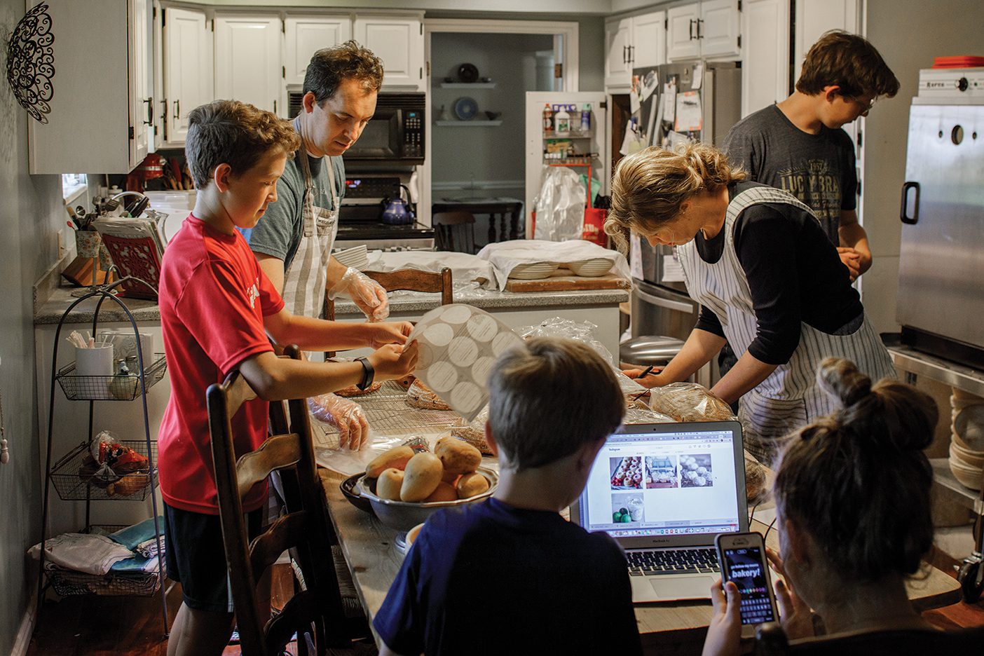 The Nielson family is gathered around their kitchen table as they package cinnamon rolls for their latest order.