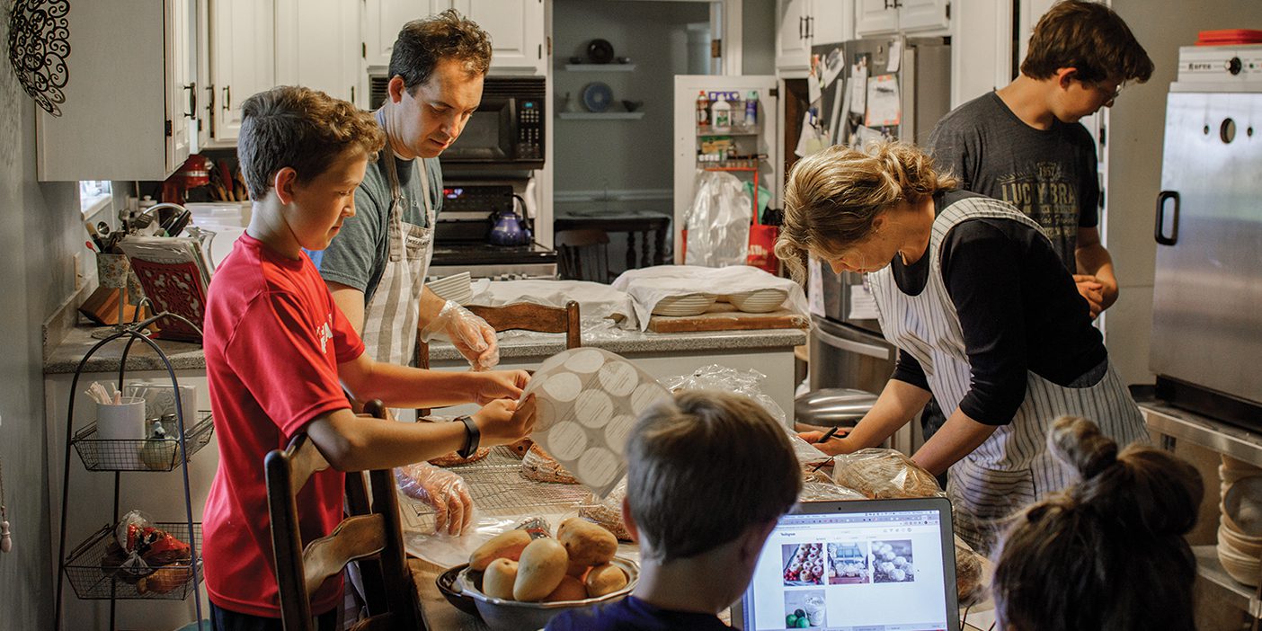 The Nielson family is gathered around their kitchen table as they package cinnamon rolls for their latest order.