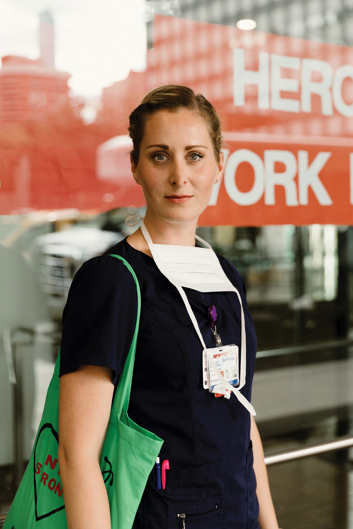 ICU nurse Channing Voyles with a somber face in scrubs and a face mask.