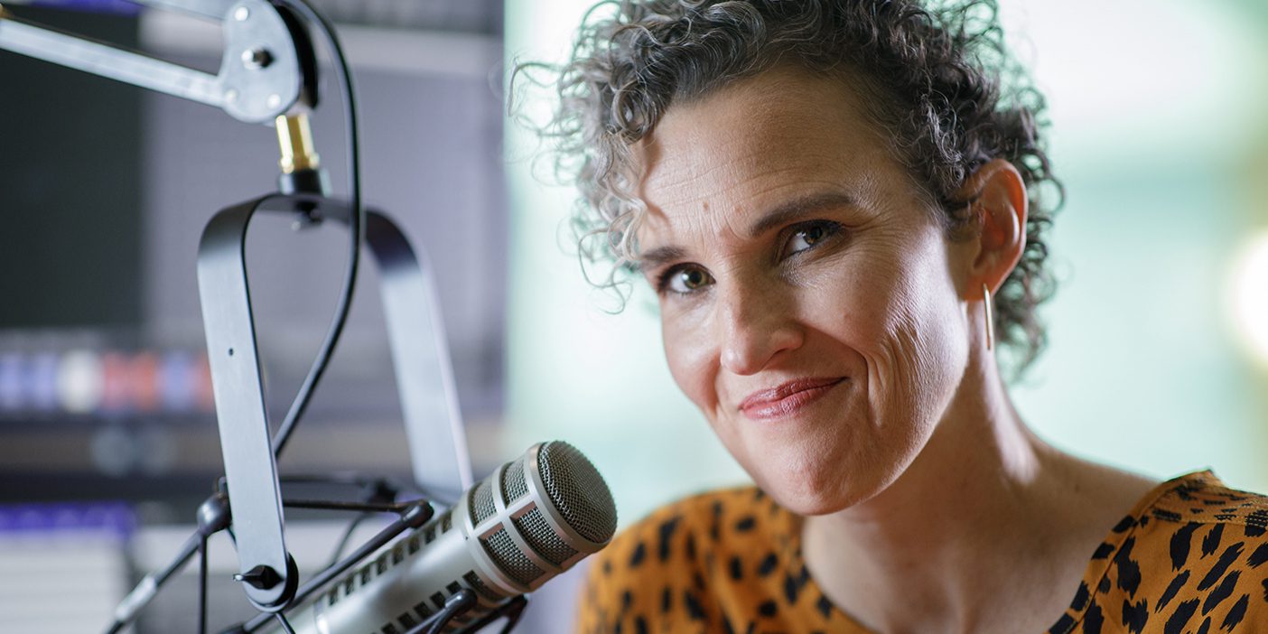 A portrait of Top of Mind host Julie Rose next to a microphone.