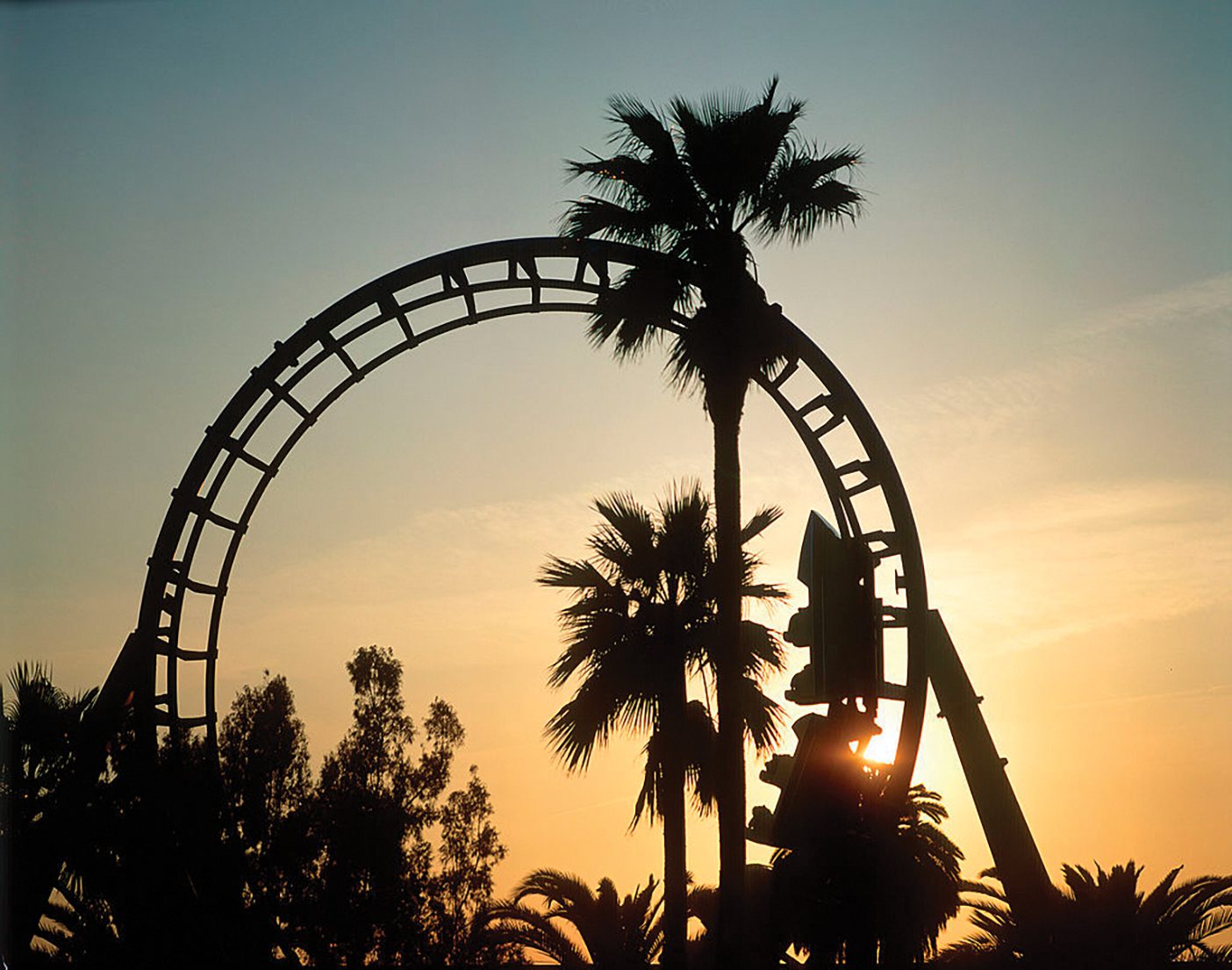 Roller coaster loop silhouetted at sunset