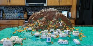 A model of BYU campus, complete with Y Mountain, made from rice crispy treats are displayed on a green table cloth.