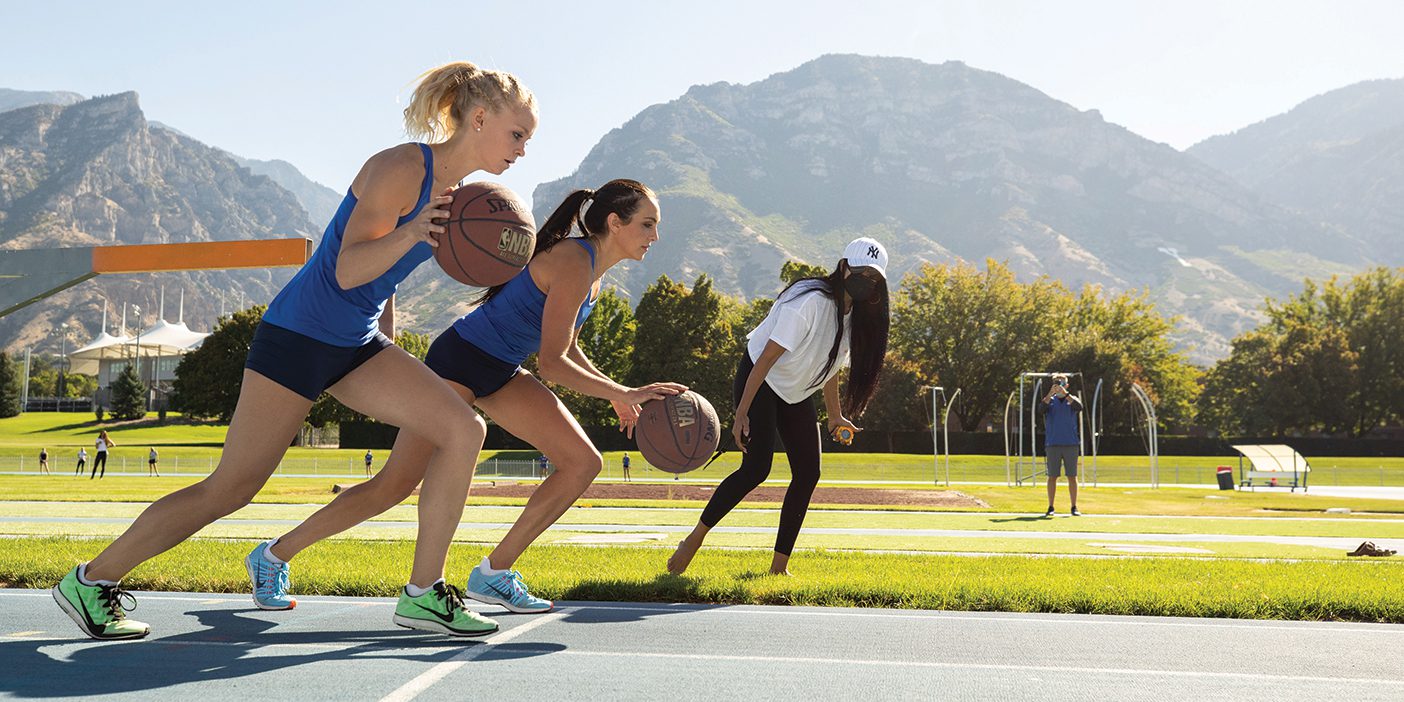 BYU track and field runners Whittni Orton and Anna Camp Bennett dribbling basketballs as they run a mile on the BYU track.