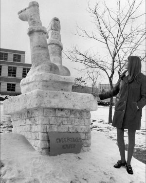 A snow sculpture depicts Santa stuck upside-down in a chimney.