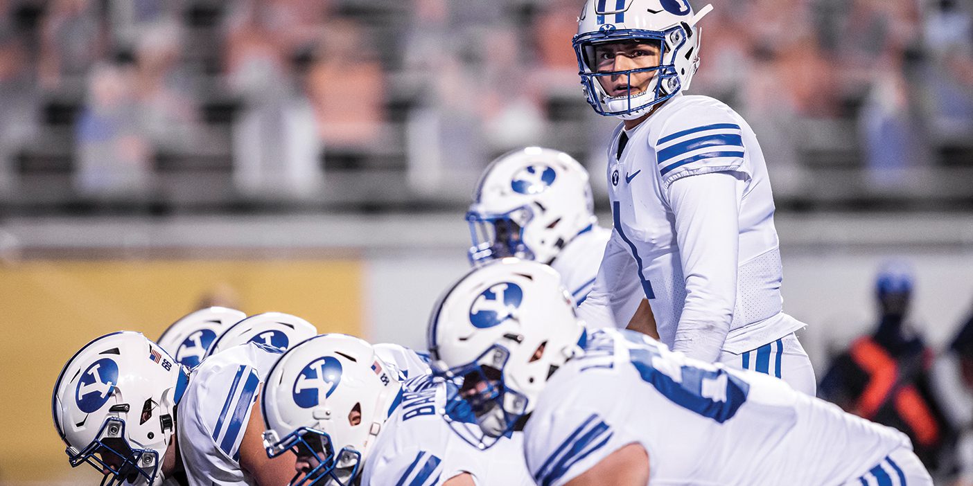 BYU quarterback stands behind the offensive line.