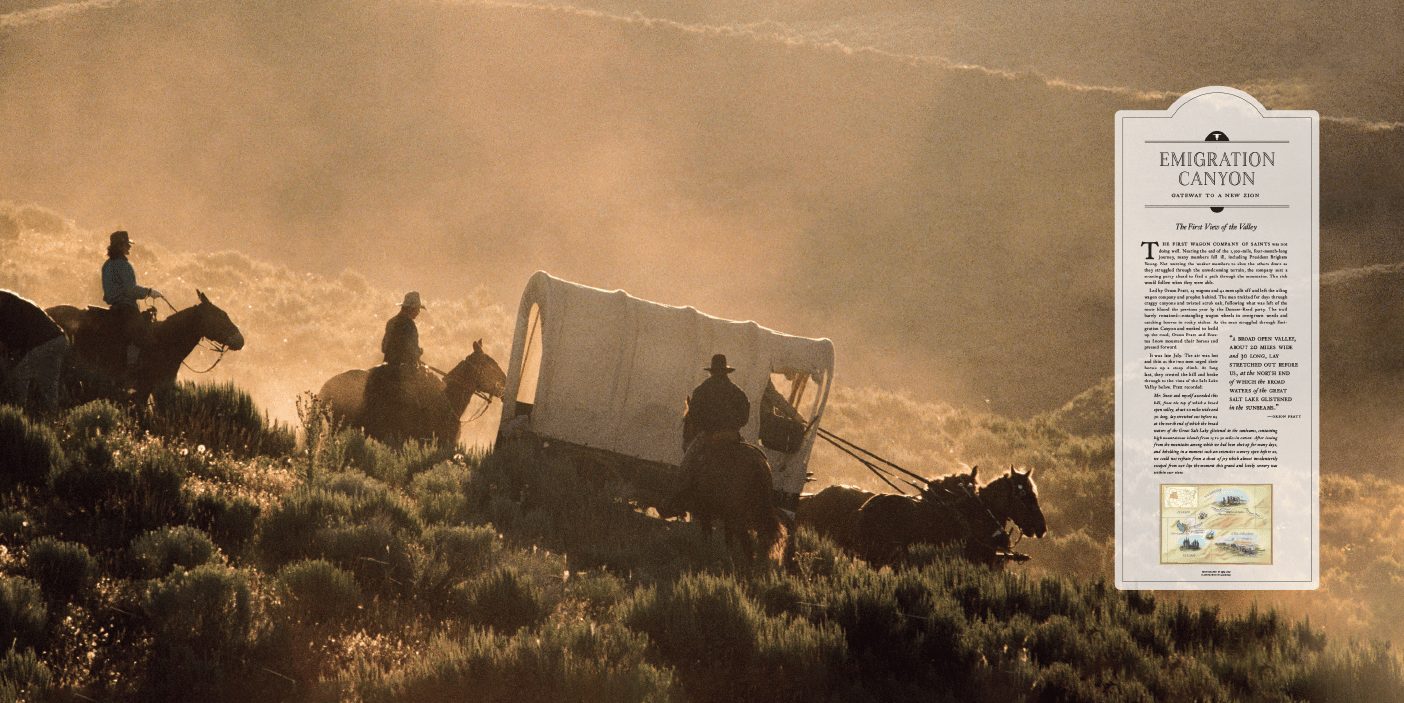 A covered wagon pulled by horses through a desert mountain pass.