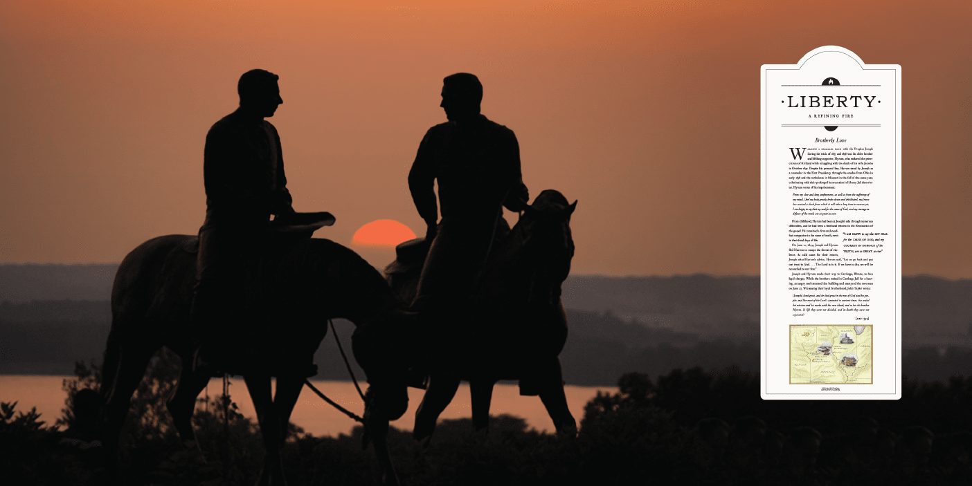 A silhouetted statue of Joseph and Hyrum Smith on horseback at dusk.