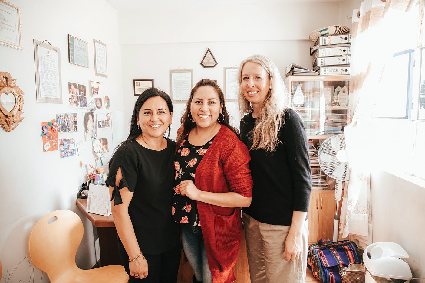 Three women, the founders of Yapay Bolivia, pose for a photo together in someone's home.