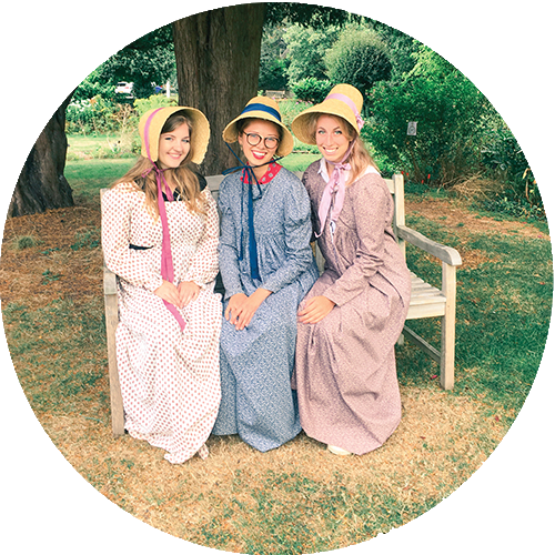 Nicole Jacobsen, Lexi Nilson, and Devynn Dayton dressed in Regency dresses and bonnets, sitting on a bench.