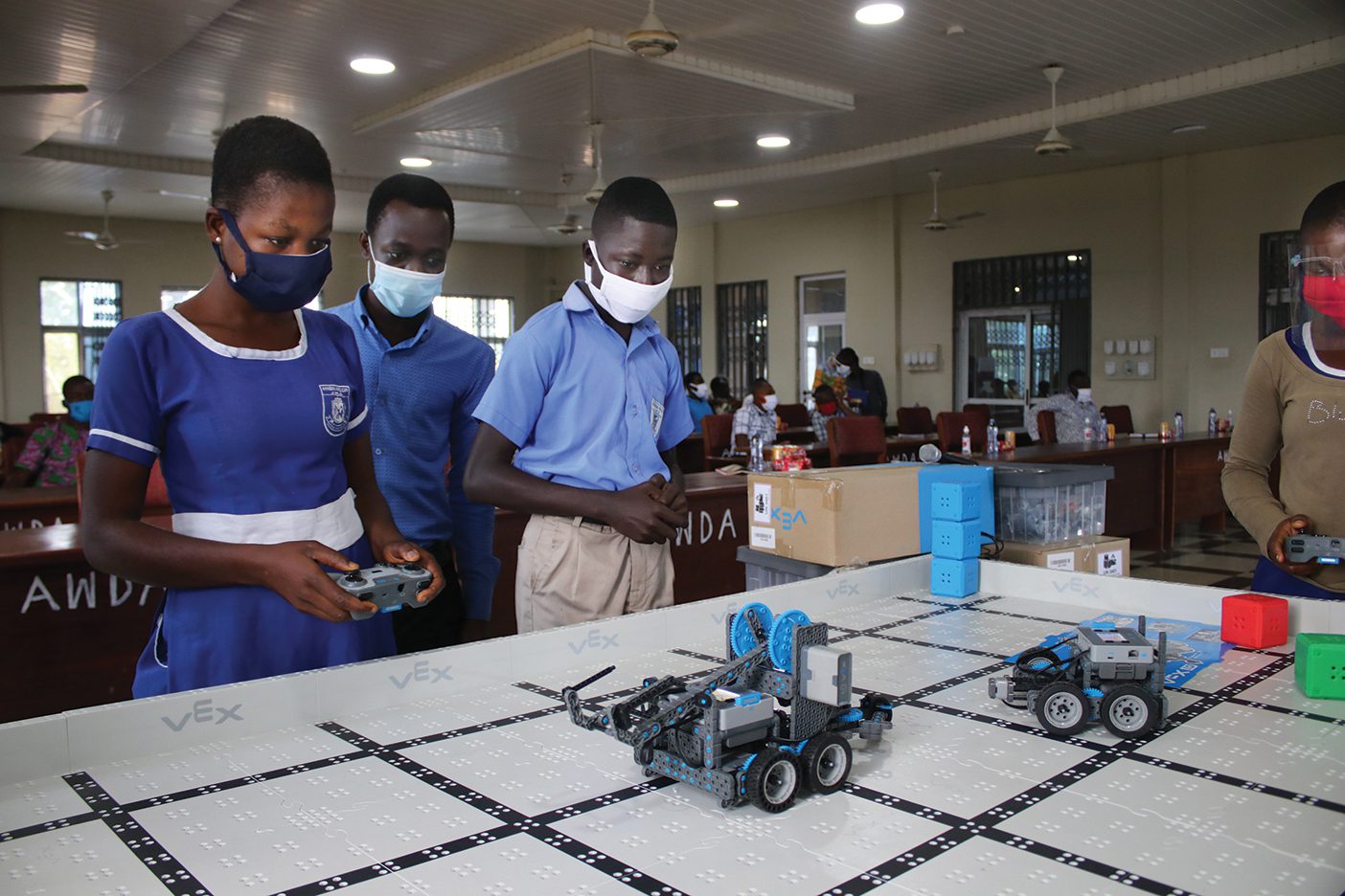 A group of Ghanian school children operate small robotic cars.