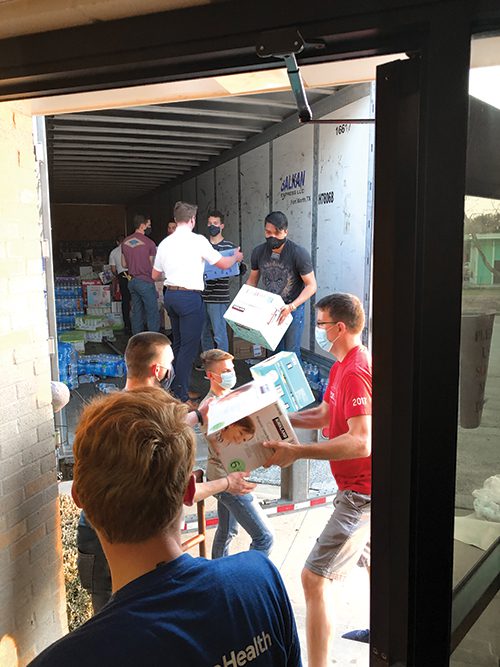 Several volunteers and a missionary unload boxes of supplies from a moving truck.