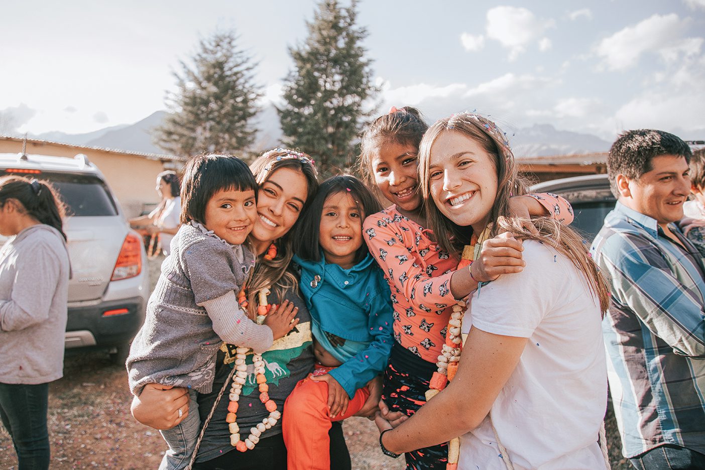 Two Yapay Bolivia volunteers hold three Bolivian children, all smiling.