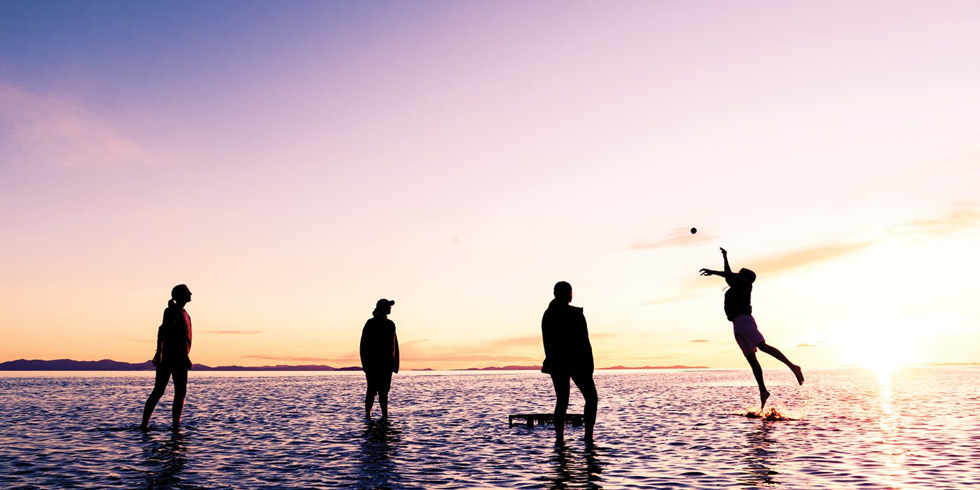 BYU students playing Spikeball on the shores of the Great Salt Lake at sunset.