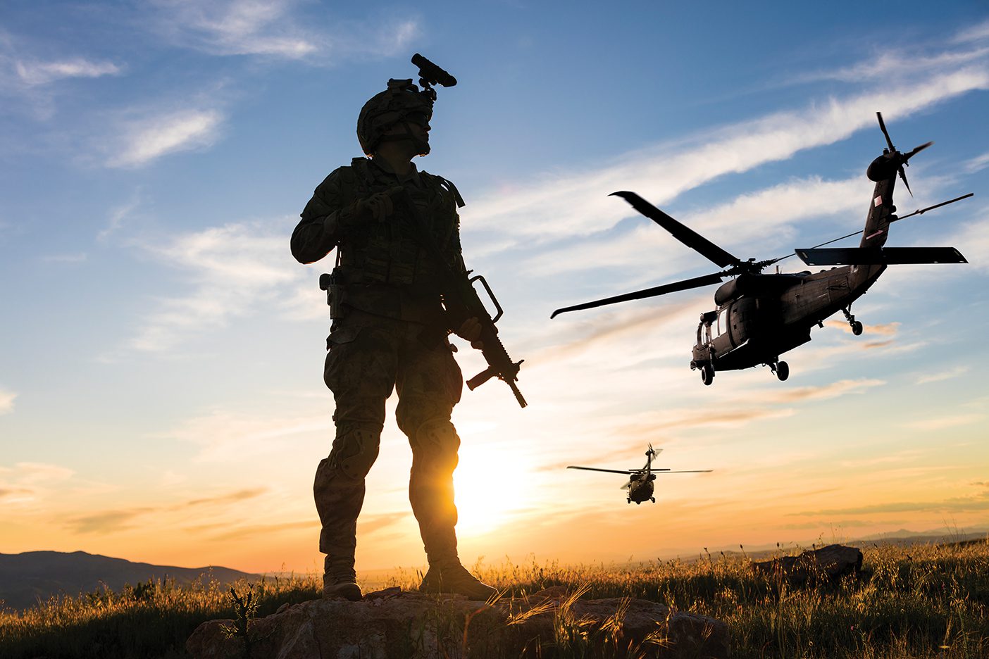 Soldier standing on the battlefield looking into the sky at helicopters.
