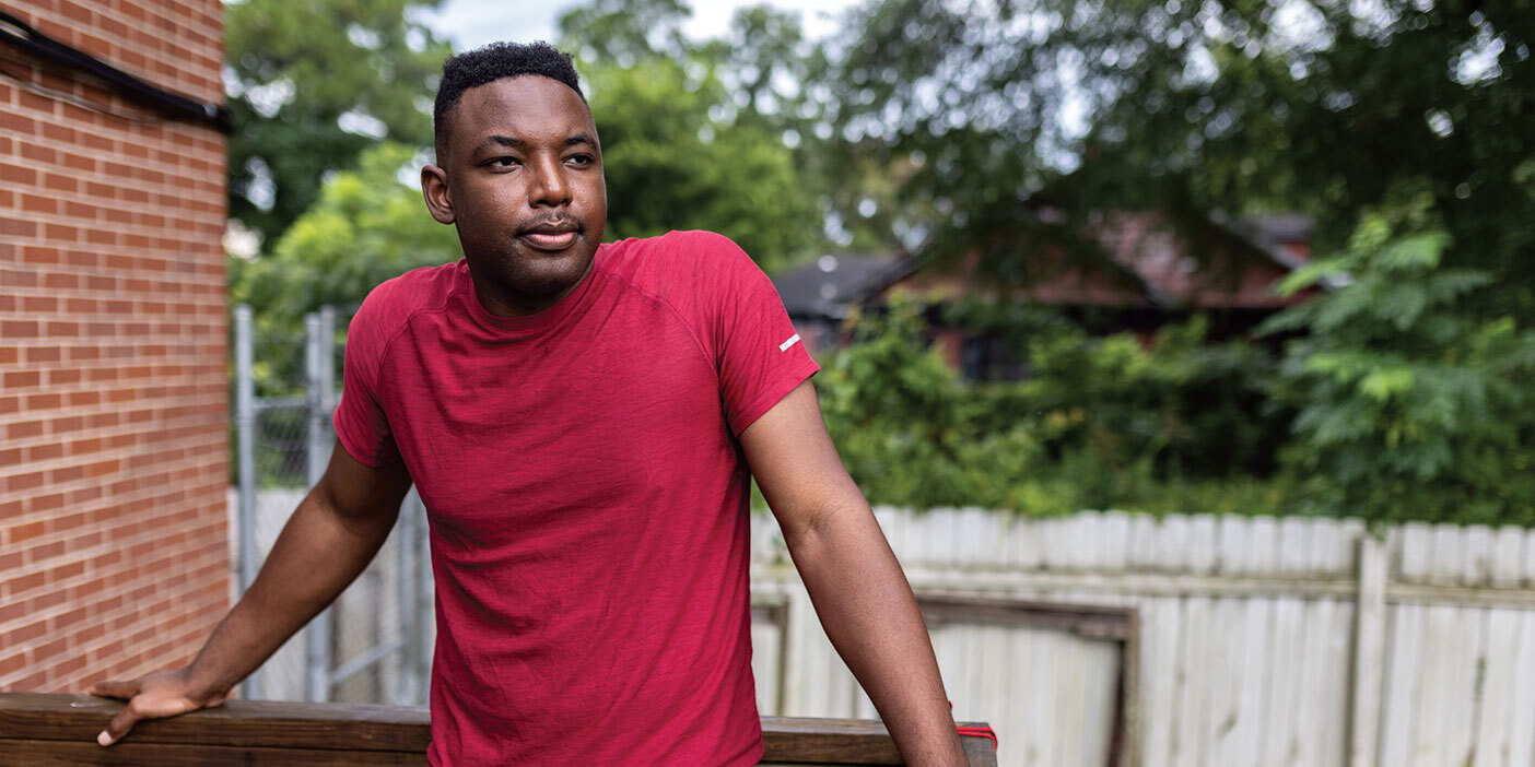 A man in a red shirt stands on a deck.