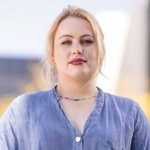 A woman in a blue blouse looks at the camera