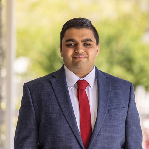 A man wears a suit and looks into the camera.