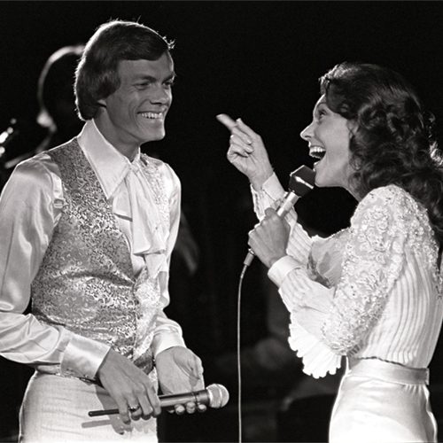 Two performers banter onstage at a Carpenter concert in 1976.